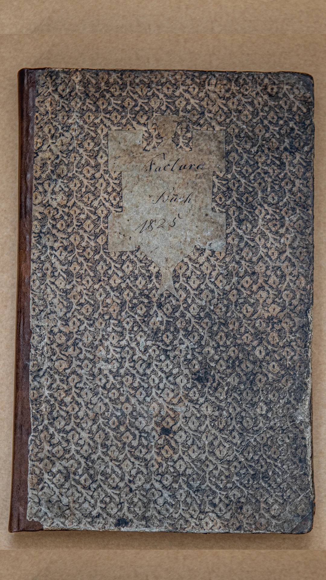 „In Pappdeckel mit Lederrücken und Lederecken gebunden und mit heute natürlich verblichenem Buntpapier überzogen, zeigt es auf dem vorderen Außendeckel ein mit der Hand geschnittenes Schildchen im Geschmack der damaligen Zeit, […] Die Handschrift auf dem Schildchen ist die gleiche wie im Buche selbst; gewisse Unterschiedlichkeiten im Duktus treten zwar auf, scheinen aber nur darauf zu deuten, daß der Schreiber in Ruhe oder in Eile seine Eintragungen gemacht hat. Dieser Kontrast tritt schon in dem Schildchen des Buches in Erscheinung, denn es ist ja mit Geduld ausgeschnitten, die Schrift aber ist flüchtig und nicht eben glücklich in den Raum gesetzt.”, so beschreibt Wilhelm Vershofen in seinem Standardwerk „Die Anfänge der chemisch-pharmazeutischen Industrie” 1949 den Deckel von Friedrich Kochs Fakturabuch. ©Axel Nixdorf